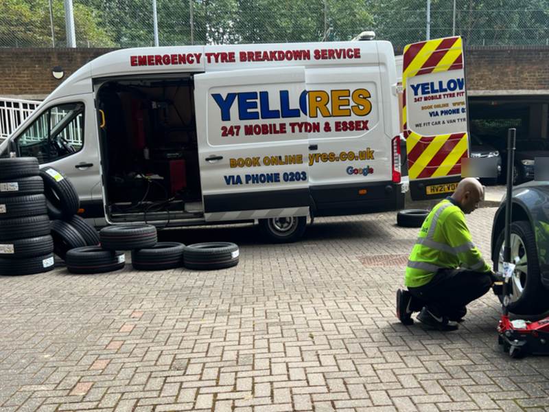 Our fitter in hi-vis fitting a wheel on a block-paved forecourt beside the van – Yellow Tyres mobile tyre fitting