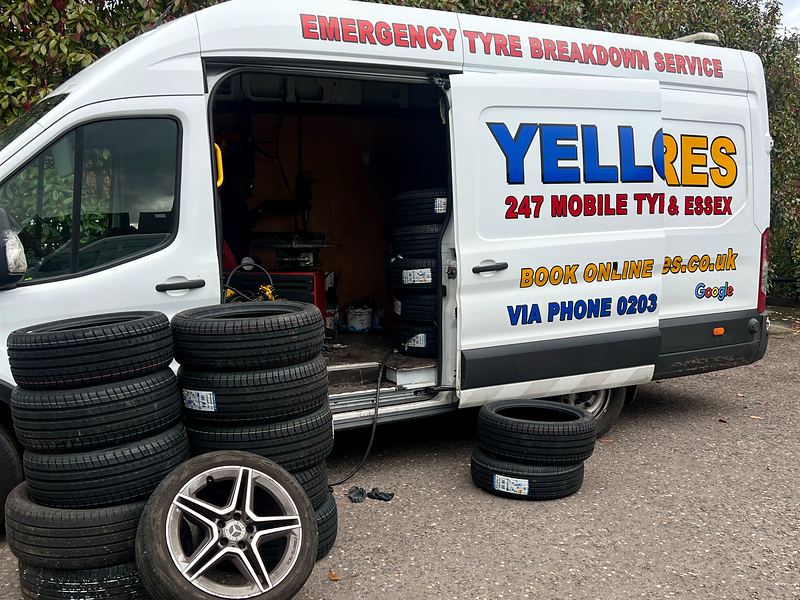 Yellow Tyres van with side door open, new tyres stacked beside an alloy wheel ready for fitting