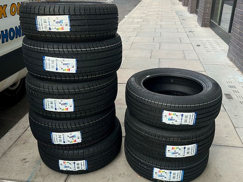 Two stacks of new tyres with EU tyre labels on a London pavement next to the Yellow Tyres van
