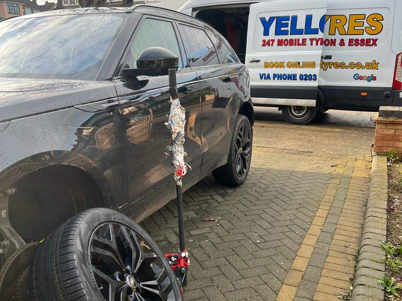 Black Range Rover on a jack on a driveway with a new Pirelli tyre and alloy ready to fit, Yellow Tyres van behind
