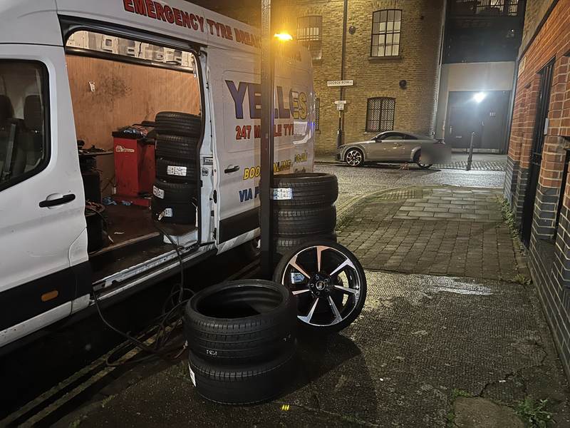 Yellow Tyres van at night with its tyre machine inside, new tyres and an alloy wheel on the cobbles