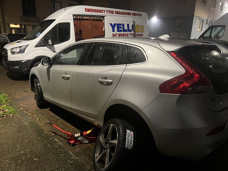 A Volvo V40 jacked up for a tyre change on a wet night, our van behind – Yellow Tyres emergency tyre call-out service, covering Bow